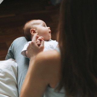A young mother looks down at a baby lying in her lap