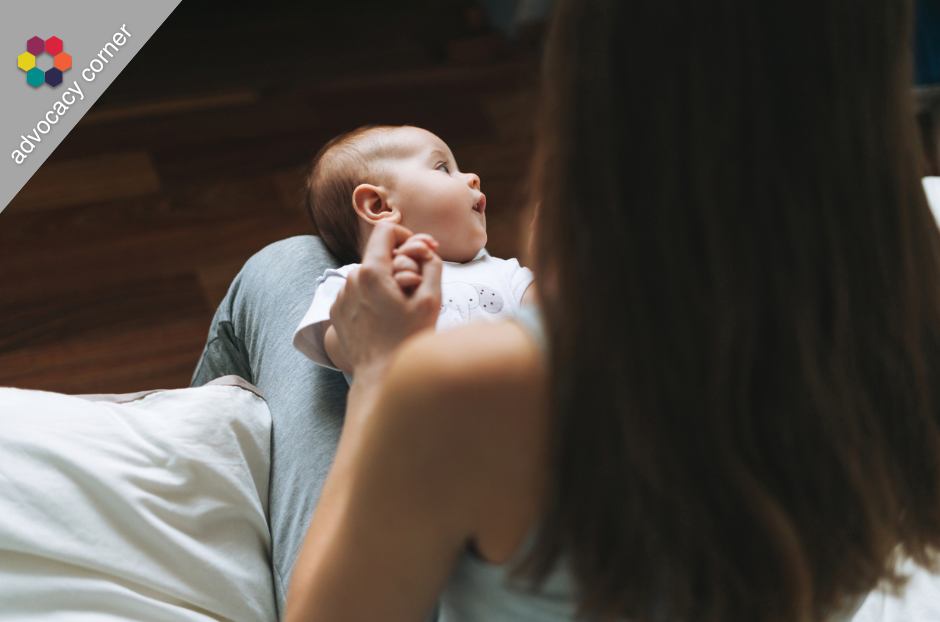 A young mother looks down at a baby lying in her lap