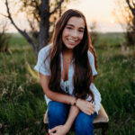 A young woman with long dark hair posing in the sunset