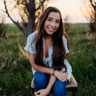 A young woman with long dark hair posing in the sunset