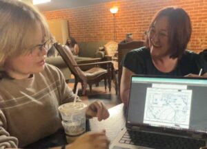 Two woman at a table viewing an image on a laptop