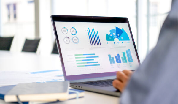 Close up of businessman using a laptop with graphs and charts on a laptop computer. The mans hands can seen typing on a keyboard.