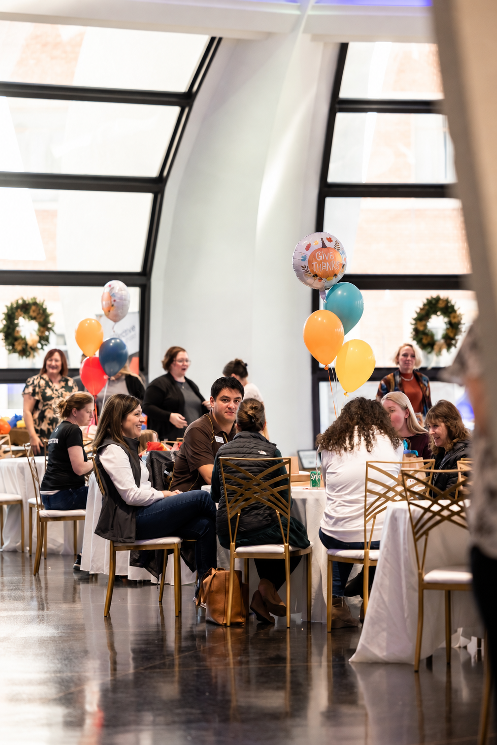 Guests talking at tables with balloons at a past Gives Thanks